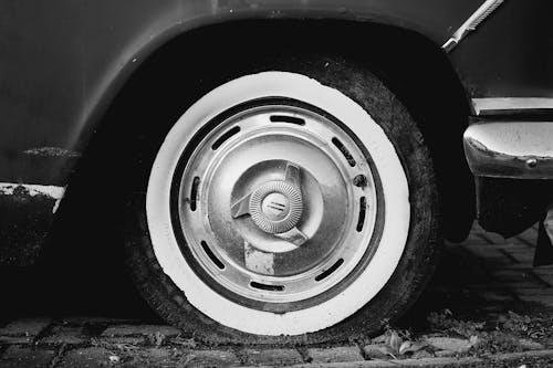 A close-up of a flat tire on a car parked on the roadside at night, with hazard lights flashing.
