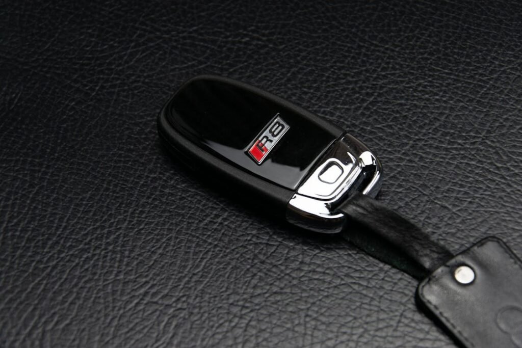 A black car key fob resting on a brown leather surface.