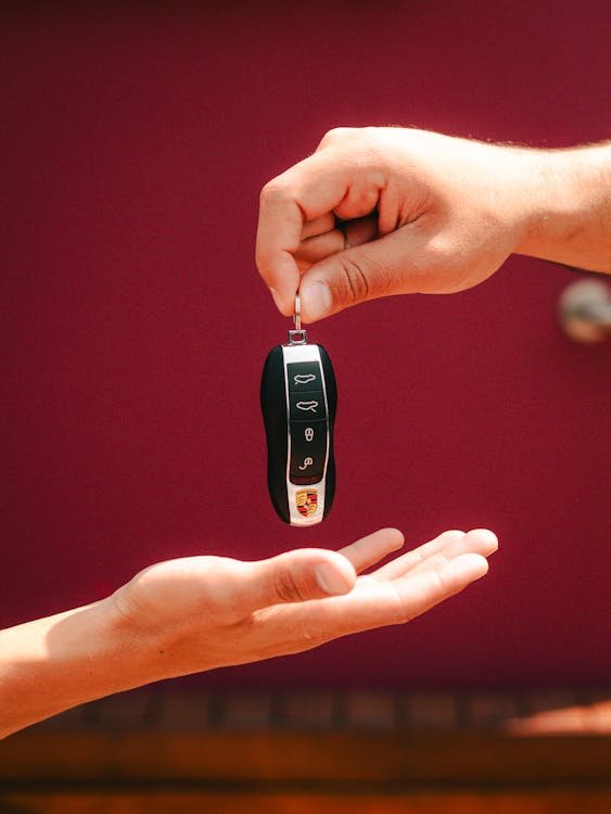 A person giving a car key to another person