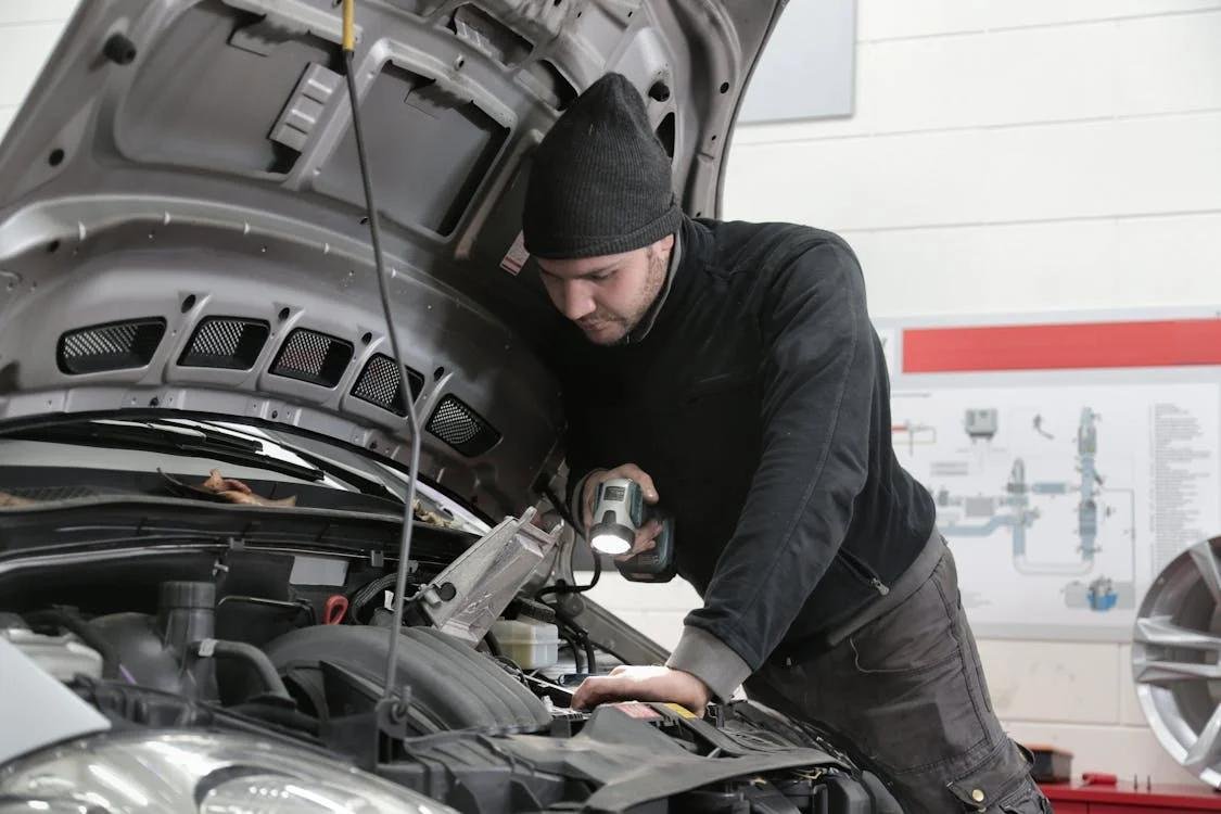 An image of a man inspecting a car battery/engine