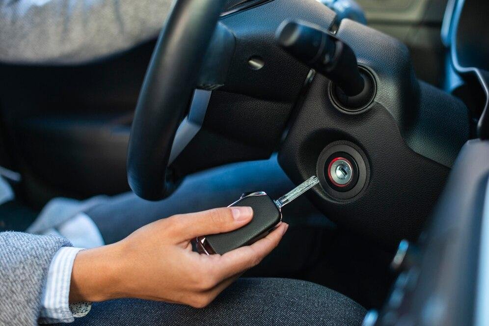 An image of a person holding a car key next to the ignition