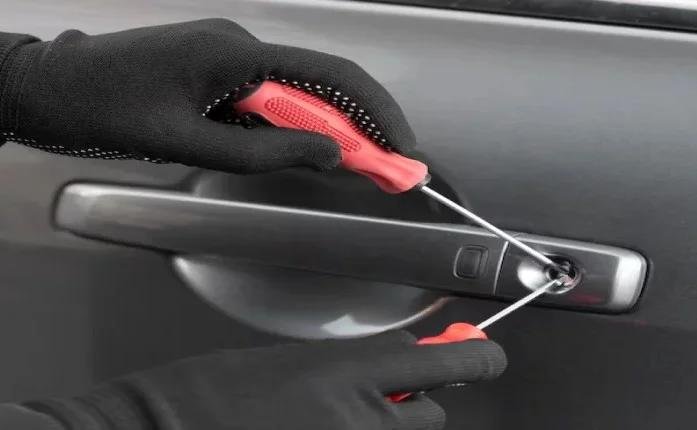 An image of a locksmith’s gloved hands using two screwdrivers to open a car door