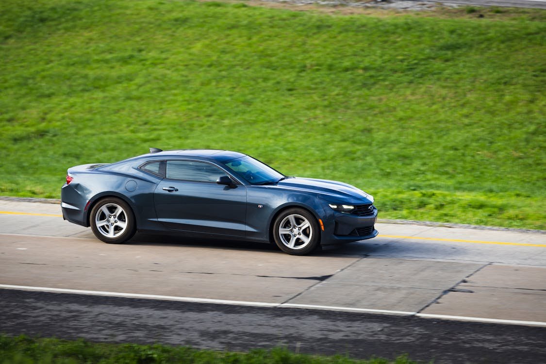 A sleek black sports car driving along a highway.