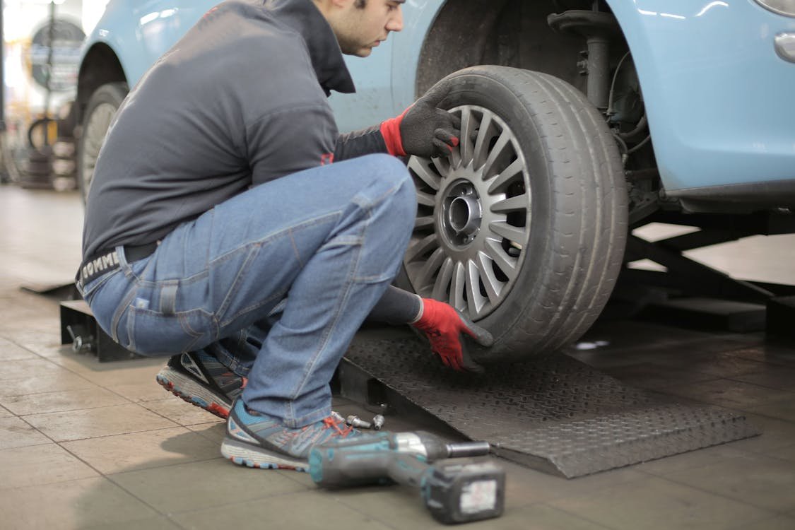 A man crouched beside a car while changing a tire