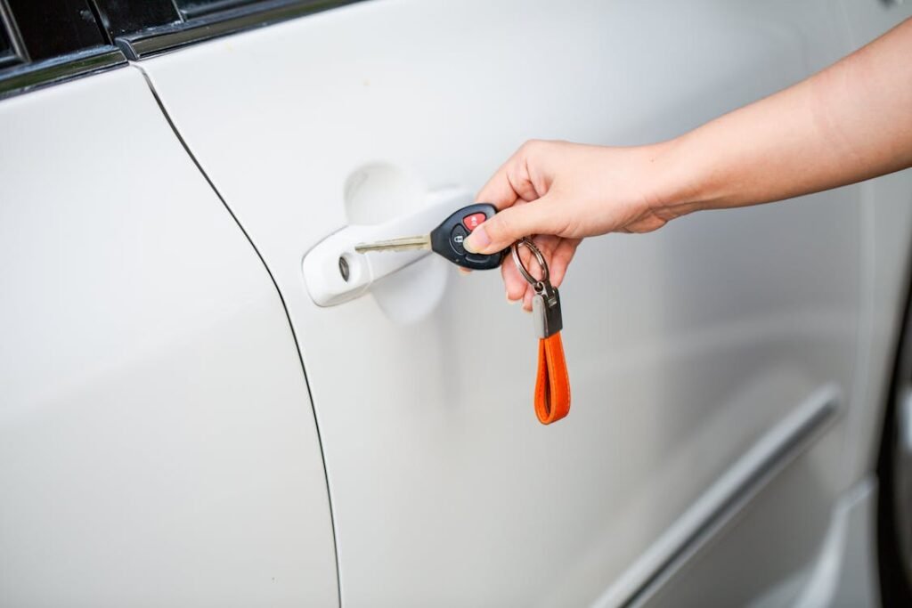 A person holding a car key near a car door.