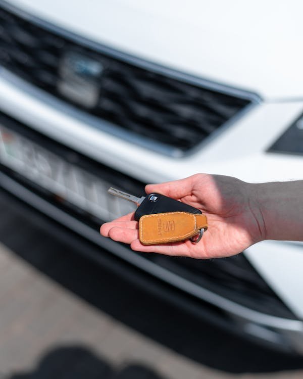 A person holding a car key near a vehicle