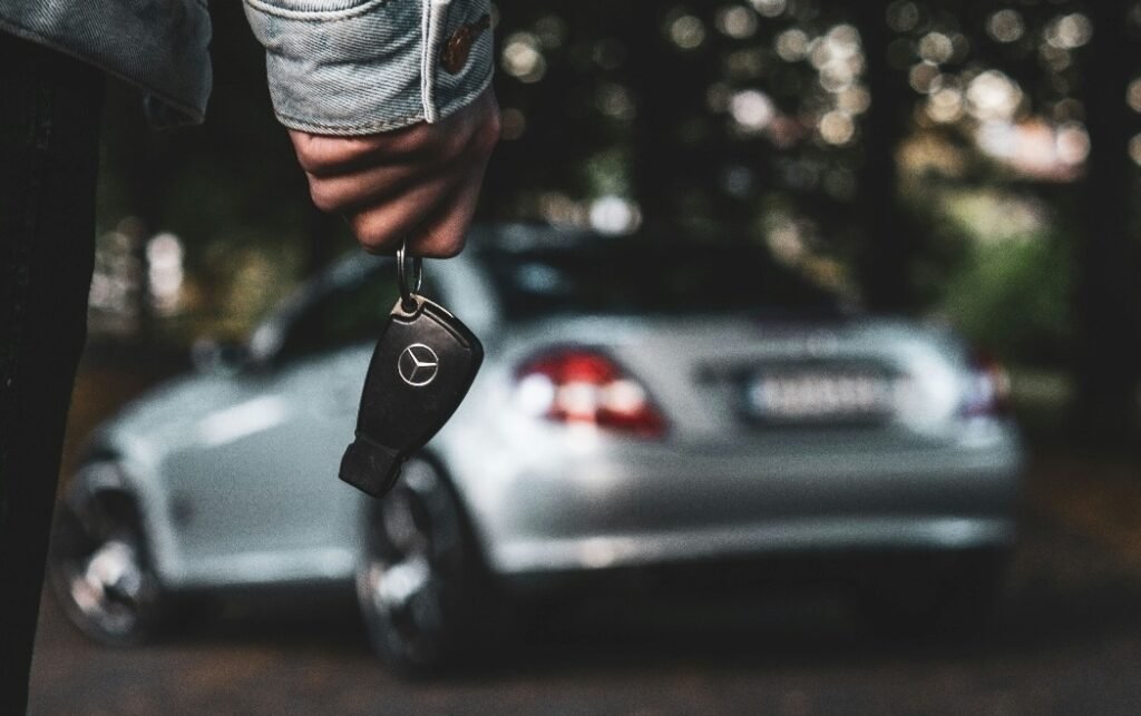 A person holding a car key with a blurred car in the background